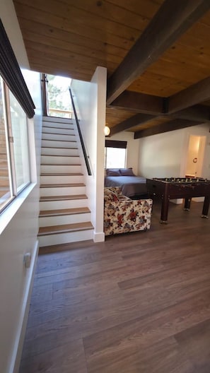Una escalera de madera que lleva a un dormitorio con una cama y una mesa de fútbol.