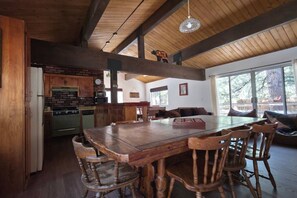 Una cocina rústica con armarios de madera, pared de ladrillo y una gran mesa de comedor con sillas de madera.