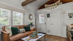 A cozy room with a brown leather sofa, a coffee table, and a white door with a sign.
