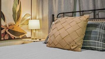 A bed with a woven pillow, a bedside lamp, and a framed artwork on the wall.