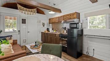 A compact kitchen with wooden cabinets, a black refrigerator, and a microwave.