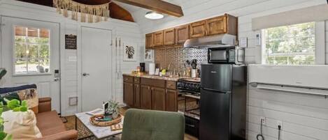 A compact kitchen with wooden cabinets, a black refrigerator, and a microwave.
