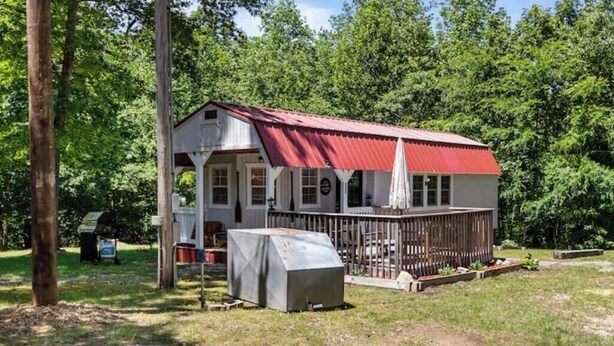 A single-story house with a red roof, a covered porch, and a fenced yard.