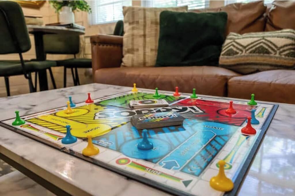A board game on a table in a living room with a couch and chairs in the background.