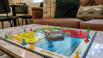 A board game on a table in a living room with a couch and chairs in the background.