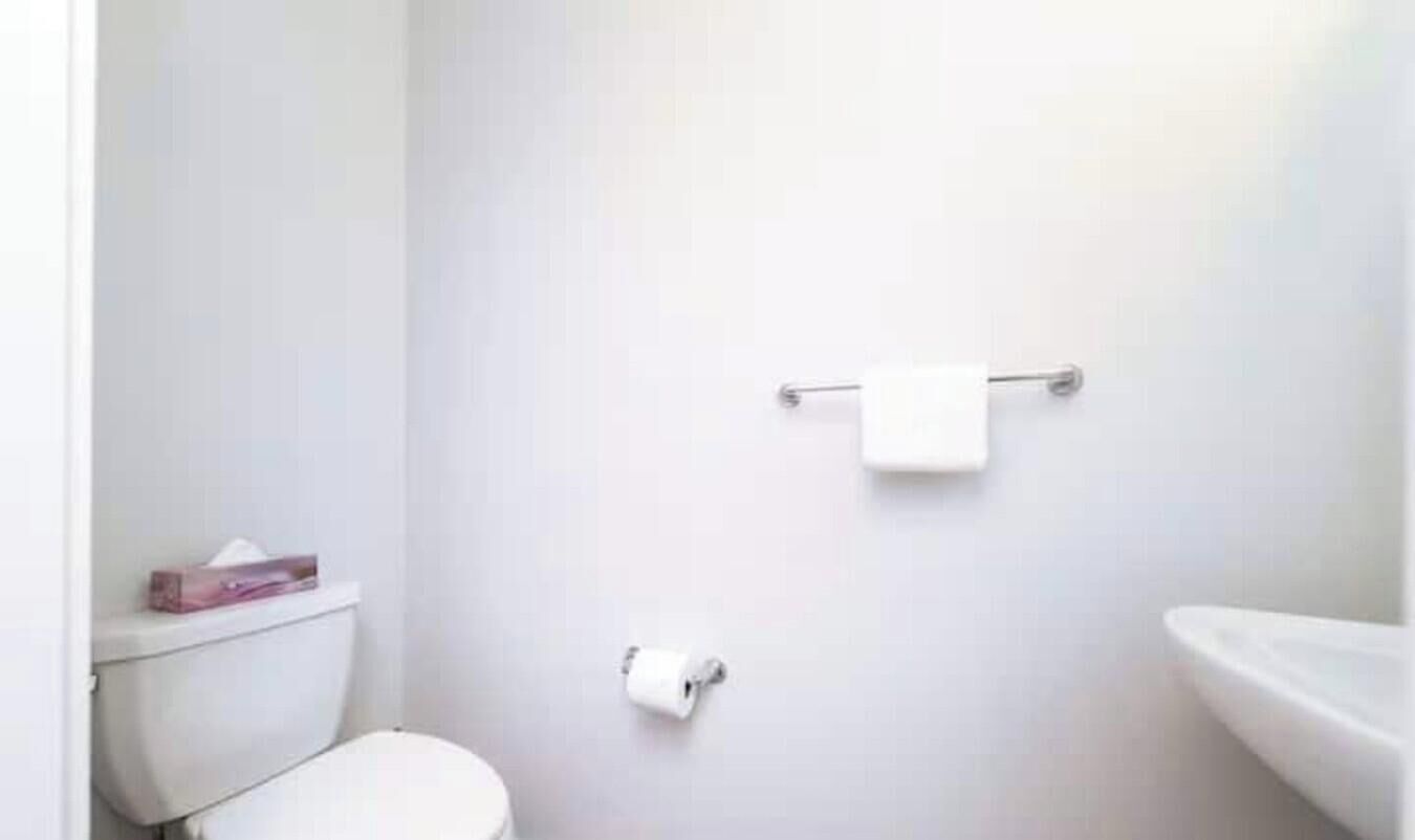 A small, white bathroom with a toilet, a towel rack, and a sink.