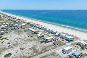 Ein Luftbild eines Küstenresorts mit Strandhäusern, einem Sandstrand und dem Meer.