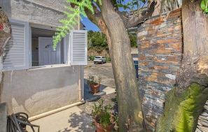 A narrow street with a stone wall, a tree, and a building with a partially open window. - 1 bedroom awesome apartment in Bastia (Bastia)