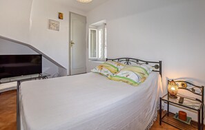 A bedroom with a bed, a television, a window, and a bedside table with a lamp. - 1 bedroom awesome apartment in Bastia (Bastia)