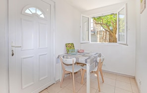 A small dining area with a table, chairs, a window with a view of a tree, and a white door. - 1 bedroom awesome apartment in Bastia (Bastia)