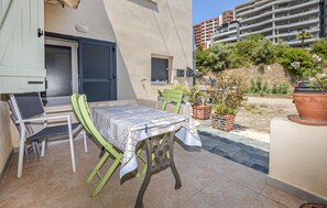 An outdoor patio with a table and chairs, a door, and a view of a multi-story building. - 1 bedroom awesome apartment in Bastia (Bastia)