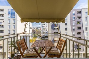 A balcony with a table and chairs, overlooking a cityscape with modern buildings. - Calm Cozy Home 1BR in Tirana (Tirana)