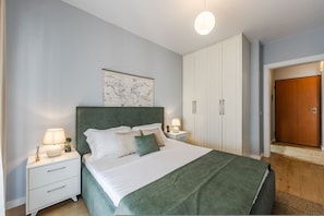 A bedroom with a bed, nightstands, a map on the wall, a wardrobe, and a door. - Calm Cozy Home 1BR in Tirana (Tirana)