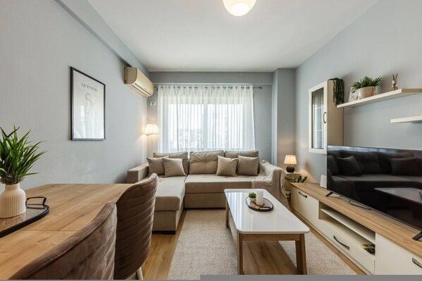 A modern living room with a sofa, coffee table, TV, and a dining area with chairs and a table. - Calm Cozy Home 1BR in Tirana (Tirana)