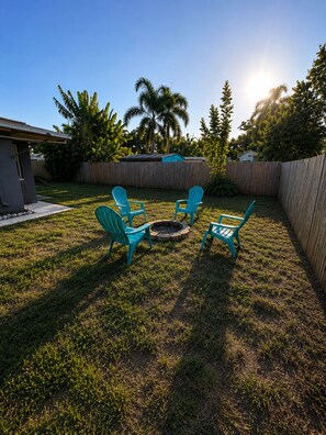 A backyard with a fire pit, four chairs, and a wooden fence. - 3BR Largo Home Near Indian Rocks & Madeira Beach (Largo)