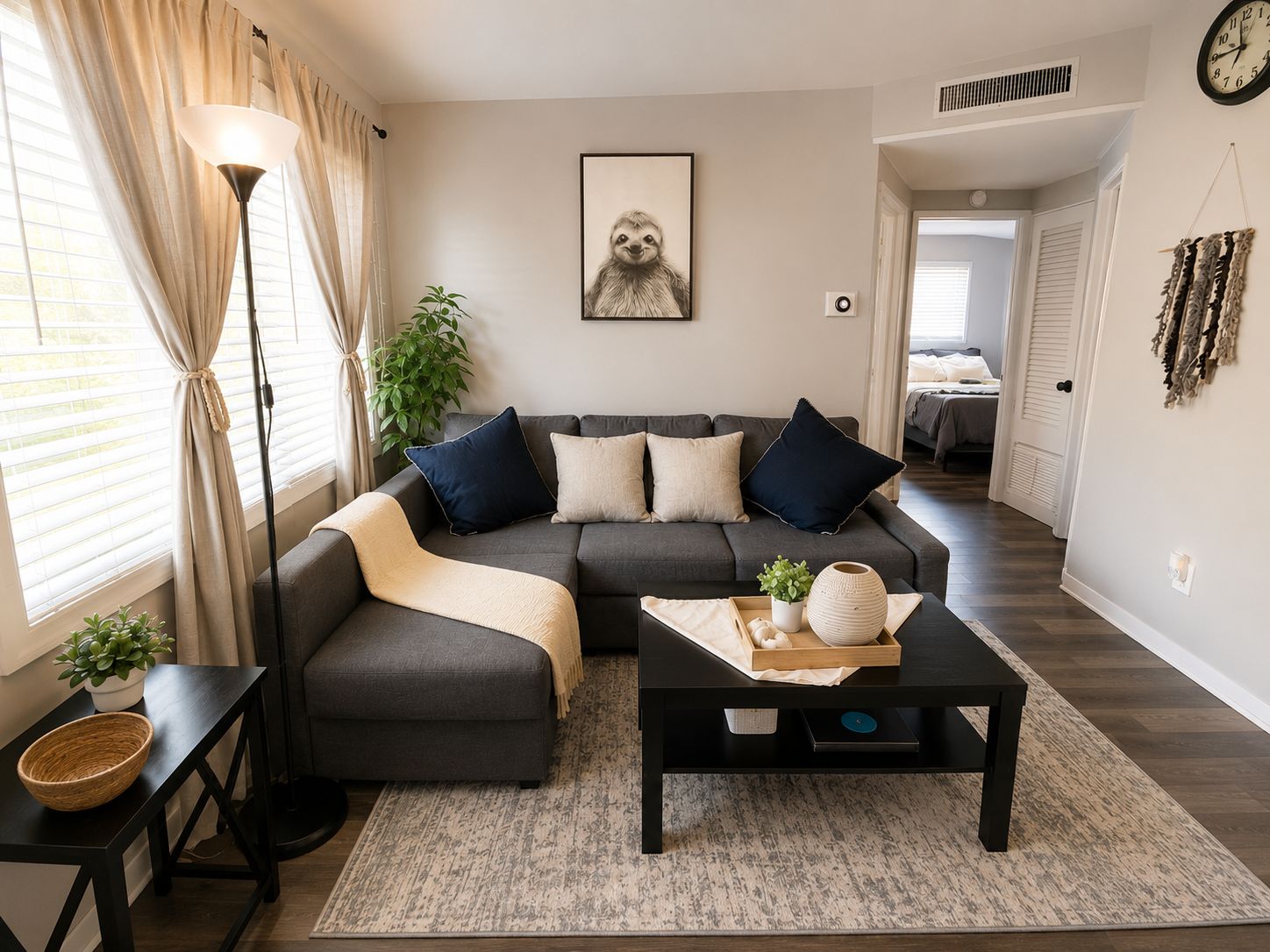 A modern living room with a sectional sofa, a coffee table, a floor lamp, and a framed picture on the wall.