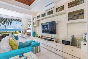 Ein modernes Wohnzimmer mit großem Fernseher, einer Couch und Blick auf den Ozean.
