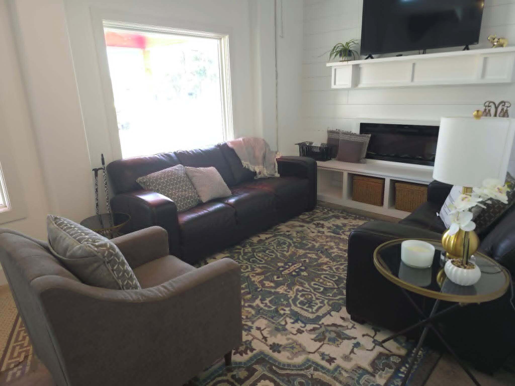 A living room with a sofa, armchair, and a TV on a stand.