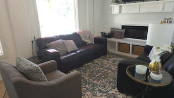 A living room with a sofa, armchair, and a TV on a stand.