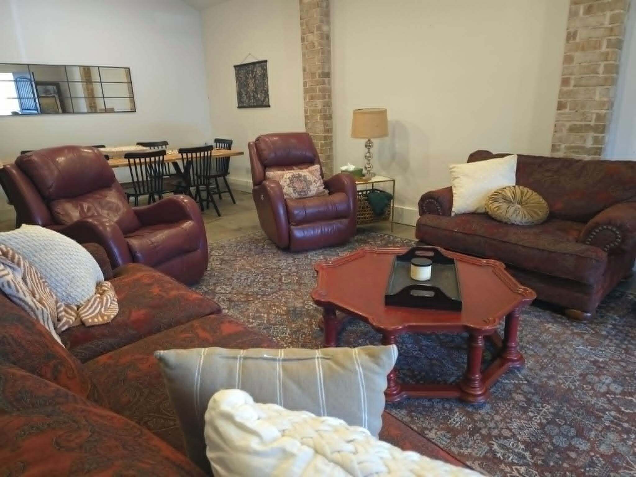 A living room with leather sofas, a coffee table, and a dining area with chairs and a table.