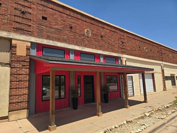 A two-story building with a red awning, brick facade, and a clear sky.