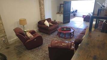 A living room with a sofa, armchair, and coffee table. There is a door leading to another room.