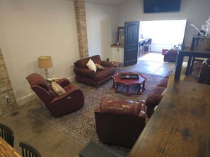 A living room with a sofa, armchair, and coffee table. There is a door leading to another room.