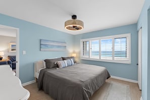 Ein Schlafzimmer mit Bett, Deckenventilator, Fenster mit Jalousien und einem Gemälde an der Wand.