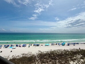 Ein Strand mit Sonnenschirmen und Liegestühlen, ein sandiger Uferstreifen und das Meer.