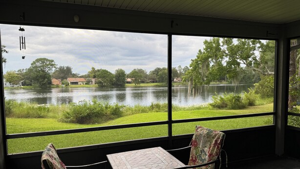 A room with a large window overlooking a lake, a table, and two chairs. - Lakefront 3-bedroom house in Sanford (Sanford)