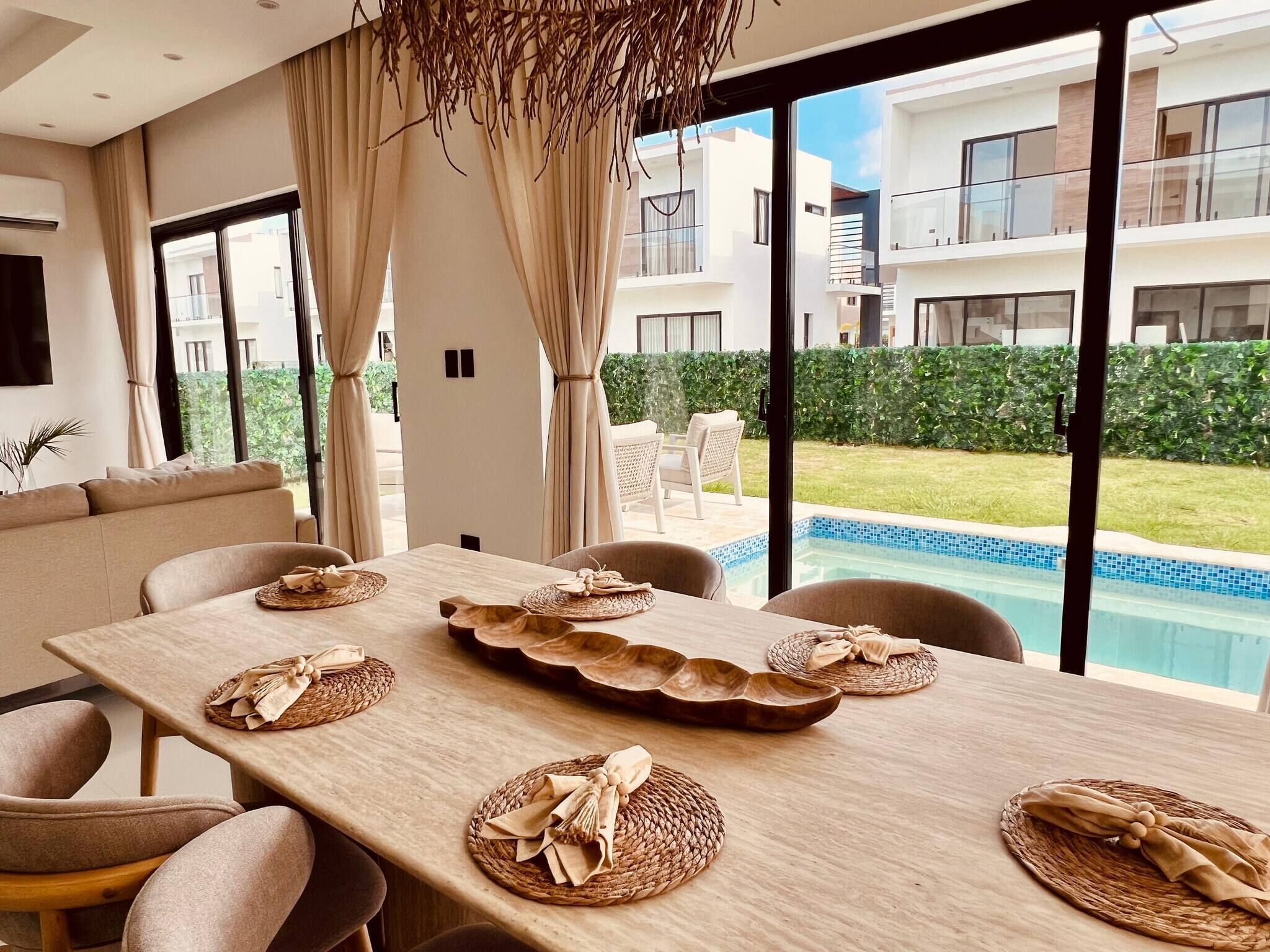Un coin repas avec vue sur la piscine, un canapé et une table décorée avec des sets de table et un centre de table.