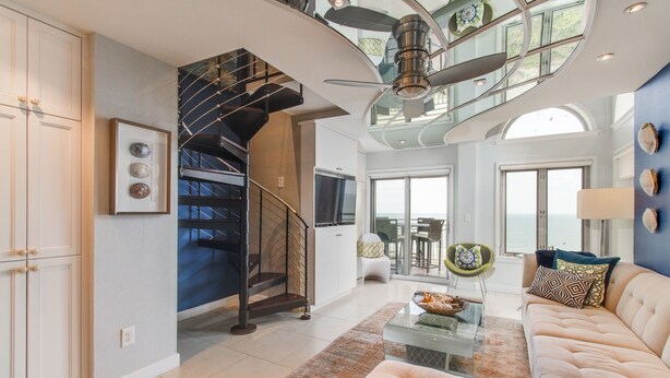 A spacious living area with a modern staircase, a glass coffee table, and a comfortable sofa. - Oceanfront Penthouse | 6th Floor Views + 2 King Suites (Kiawah Island)