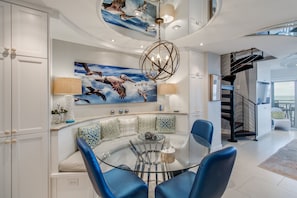 Ein modernes Interieur mit einer gebogenen Sitzecke, einem Glastisch und einer Treppe.