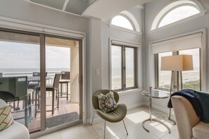 Ein modernes Zimmer mit Balkon, einem Sessel mit Zierkissen, einem runden Tisch und einer Lampe.