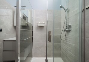 Uma casa de banho moderna com cabine de duche em vidro, lavatório branco e armário embutido.