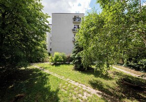 A pathway leading to a building surrounded by greenery. - Asfaltowa Mokotów City Apartment (Warszawa)