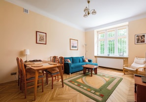 Ein Wohnzimmer mit Holzesstisch, blauem Sofa und einem Teppich mit grünem Muster.