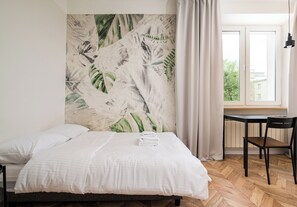 A bedroom with a bed, a window with curtains, a desk, and a chair. - Żytnia City Comfort Studio #5A (Warszawa)
