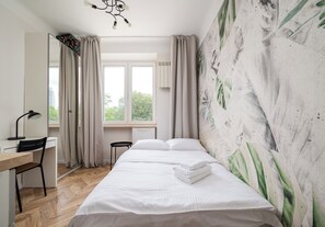 A bedroom with a bed, a desk, a chair, and a window with curtains. - Żytnia City Comfort Studio #5B (Warszawa)