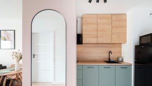A modern kitchen with light wood cabinets, a black sink, and a black refrigerator. - Łódź Downtown Charm Apartment (Łódź)