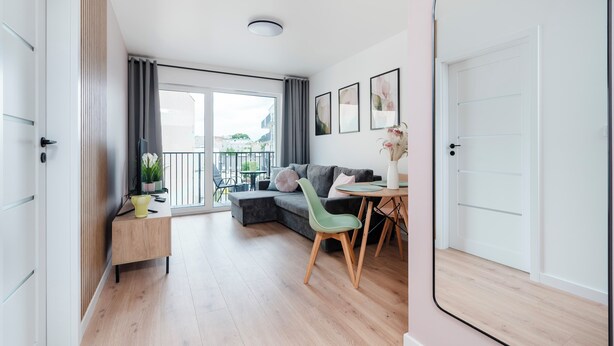 A modern apartment with a balcony, a sofa, a dining table, and a TV. - Łódź Downtown Charm Apartment (Łódź)