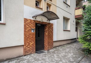 Een gebouw met een gevel van baksteen, een zwarte deur en een metalen luifel.
