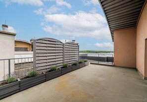 Una terraza en la azotea con una reja de metal, piso de concreto y vista al cielo.