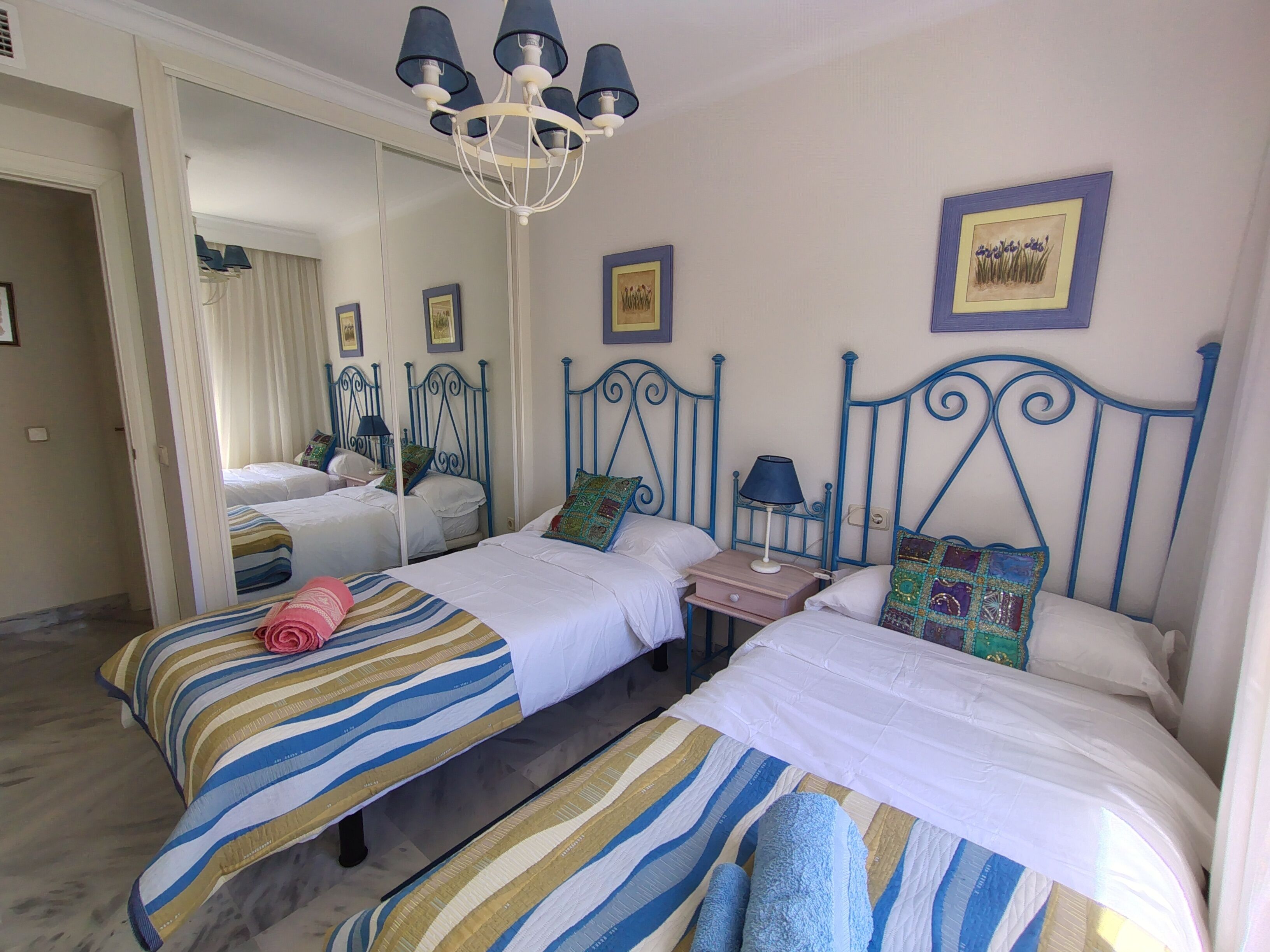 Een hotelkamer met twee bedden, een kroonluchter, een spiegel en wanddecoraties.