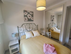 A bedroom with a bed, bedside tables, a mirror, and a painting on the wall. - Relax in Banus - 3 bedrooms, pools, paddle - Pass the Keys (Marbella)