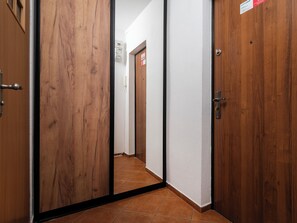 A hallway with wooden doors, a tiled floor, and a sign on the wall. - Atlas Arena Standard Studio (Łódź)