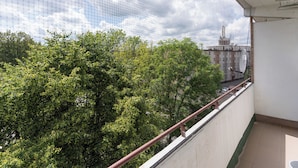 Ein Balkon mit Blick auf Bäume und Gebäude, einem Geländer und einem klaren Himmel.
