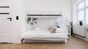 A bunk bed with white bedding, a small plant, and a radiator. - Skierniewicka Charm Studio (Łódź)