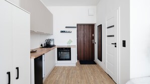 A compact kitchen with white cabinets, a wooden countertop, a built-in oven, and a wooden door. - Skierniewicka Charm Studio (Łódź)
