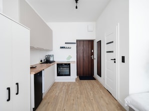 A compact kitchen with white cabinets, a wooden countertop, a built-in oven, and a wooden door. - Skierniewicka Charm Studio (Łódź)